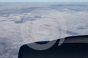 Jet engine aircraft. Blue horizon, view from the airplane`s porthole. The sky in the porthole, white fluffy clouds below.