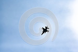 Jet fighter in backlight in blue sky