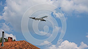 Jet passenger airplane flying above roof