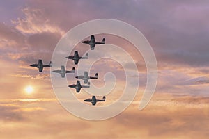 Jet planes flying in formation again a warm colored cloudscape