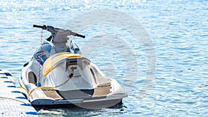 Jet ski tied by a rope to a modular floating plastic pontoon berth at seaside resort