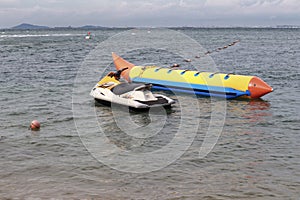 Jet ski and a yellow banana boat for family attraction at beach