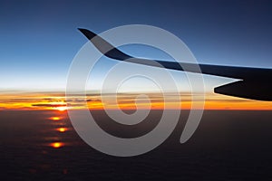 Jet in the sky at awesome sunrise. Plane wing above clouds. Beautiful view from airplane window. Morning colorful sky from plane.