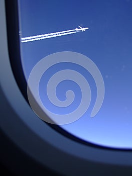 Jet trails of an airliner which was flying alongside seen through the window of my plane