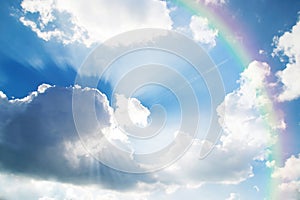 A jetliner aeroplane flying over white clouds towards a rainbow photo