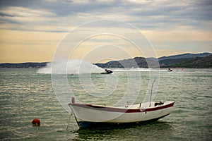 Jetski against traditional wooden fishing boats at sunset photo