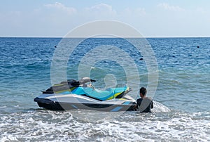Jetski floating on blue sea water. Strong power watercraft is waiting customers. Young Indonesian holding a jetbike near the shore photo