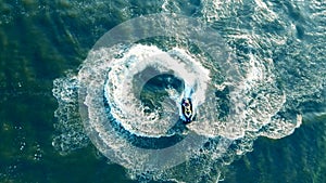 Jetskier is turning on his waterbike, waverunner across the water in a top view.