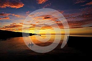 Jetskiers in the mouth of a harbour at sunset