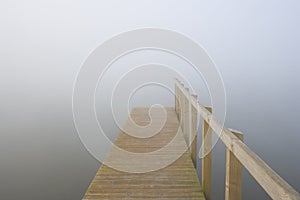 A jetty disappears into a mist covered lake photo