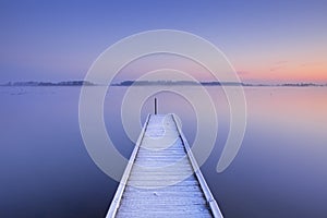 Jetty on a still lake in winter in The Netherlands