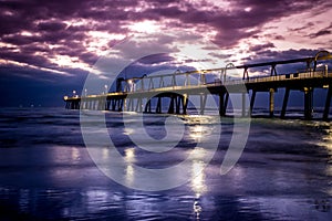 Jetty at sunrise with dramatic purple and blue clouds