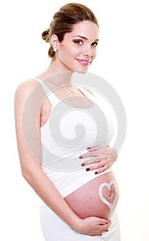 Jeune femme brune enceinte avec un coeur sur le ventre.