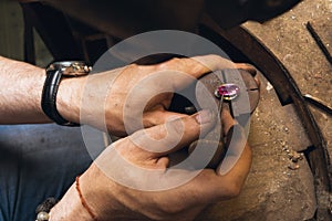 Jeweler fixes the stone in the setting of a gold ring, close-up