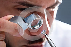 Jeweler Looking At Diamond Through Magnifying Loupe