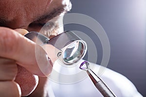 Jeweler Looking At Diamond Through Magnifying Loupe