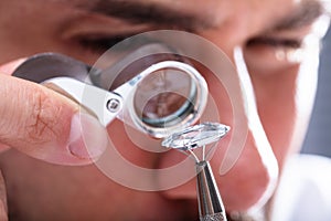 Jeweler Looking At Diamond Through Magnifying Loupe