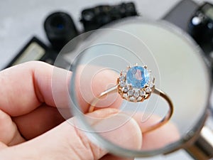 Jeweler looking at ring with blue stone, jewerly inspect and verify, pawnshop concept, jewerly shop