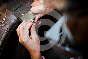 Jeweler polishes gold ring on old workbench in jewelry workshop