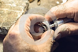 Jeweler polishing a ring using a sandpaper on a slotted mandrel.