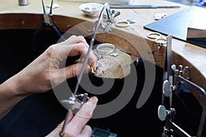 Jeweler at work in jewelery workshop, woman hands making silver thing. tools set