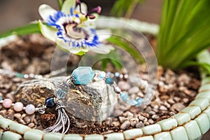 Jewelery made of natural stones against the backdrop of blossoming pasiflora. Bracelets, rings, necklaces, handmade earrings close