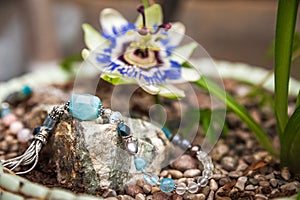 Jewelery made of natural stones against the backdrop of blossoming pasiflora. Bracelets, rings, necklaces, handmade earrings close