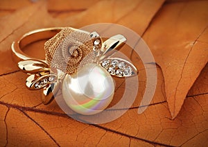 Jewelery ring with pearl on yellow leaves background