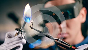 A jeweller uses welding machine while working with a ring.