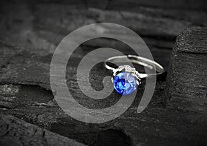 Jewellery ring witht big blue sapphir on dark coal background, s photo