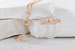 Jewellery set of hearts shape rose gold ring, pendant necklace and stud earrings on white background