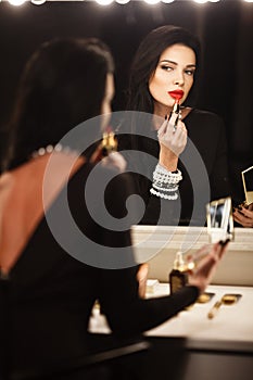 Jewelry and beauty concept. Beautiful brunette lady portrait in modern gems and black dress in studio. Woman sits by the