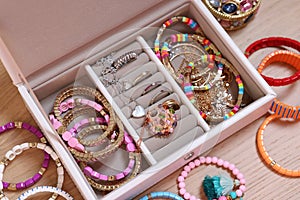 Jewelry box with stylish bracelets and other accessories on wooden table, above view