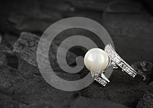 Jewelry with brilliant and pearl on black coal background, soft