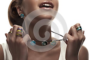 Jewelry concept. Closeup portrait of a charming female model posing isolated on a white background with colorful necklace, earring