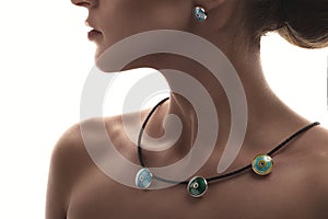 Jewelry concept. Closeup portrait of a charming female model posing isolated on a white background with colorful necklace, earring