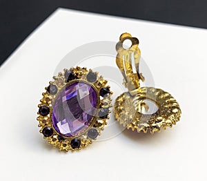 Jewelry earrings with purple and yellow gems on white background