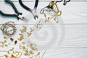 Jewelry findings handmade craft composition with pliers beads embelilshments on white wooden background
