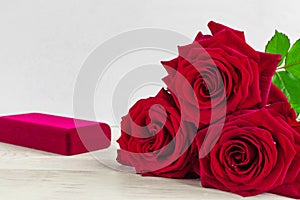 Jewelry gift box and bautiful red roses on wooden background