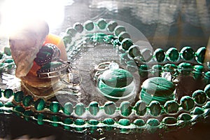 Jewelry from green malachite. Malachite beads in the studio on a glass surface with water