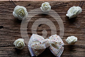 Jewelry and hair accessories. Elegant bow with holographic stones and rhinestones with a pink tint. There are cute milky roses aro