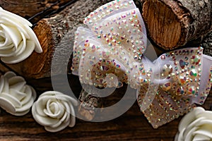 Jewelry and hair accessories. Elegant bow with holographic stones and rhinestones with a pink tint. There are cute milky roses aro