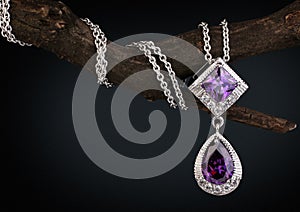 Jewelry pendant witht gem amethyst on twig, dark background photo