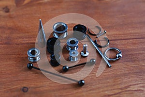 Set for piercing Piercing accessories on wooden background. a catheter for the tongue a rod in the tongue and eyebrow, earrings