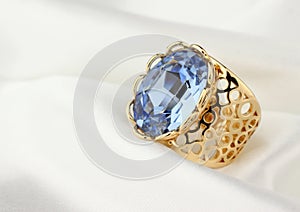 Jewelry ring with big gem on white cloth, soft focus