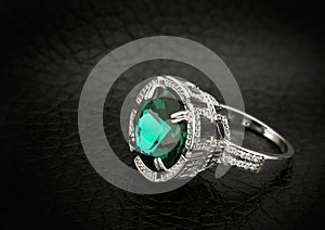 Jewelry ring with big green gem on black leather background