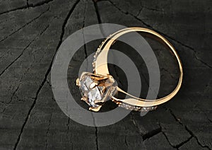 Jewelry ring with diamond on black wood background, copy-space