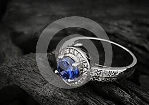 Jewelry ring witht big blue sapphir on black coal background, co photo
