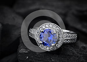 Jewelry ring witht big blue sapphir on darck coal background photo