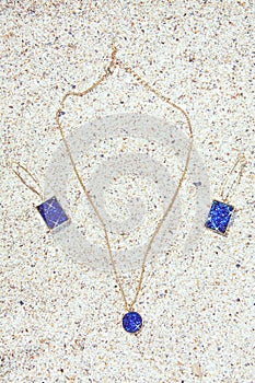 Jewelry set in aquatic shades and geometric shapes on sand beach background